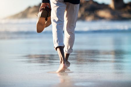 Homme marche pieds nus sur la plage