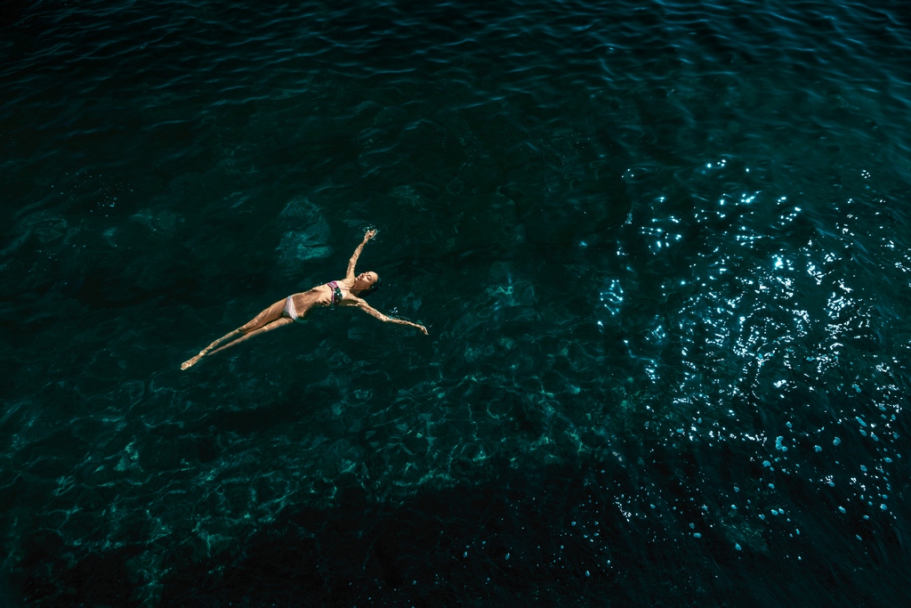 Se laisser porter par le Grand Esprit Une femme flotte paisiblement dans une vaste étendue d’eau, symbole de lâcher-prise et de confiance dans le Grand Esprit.